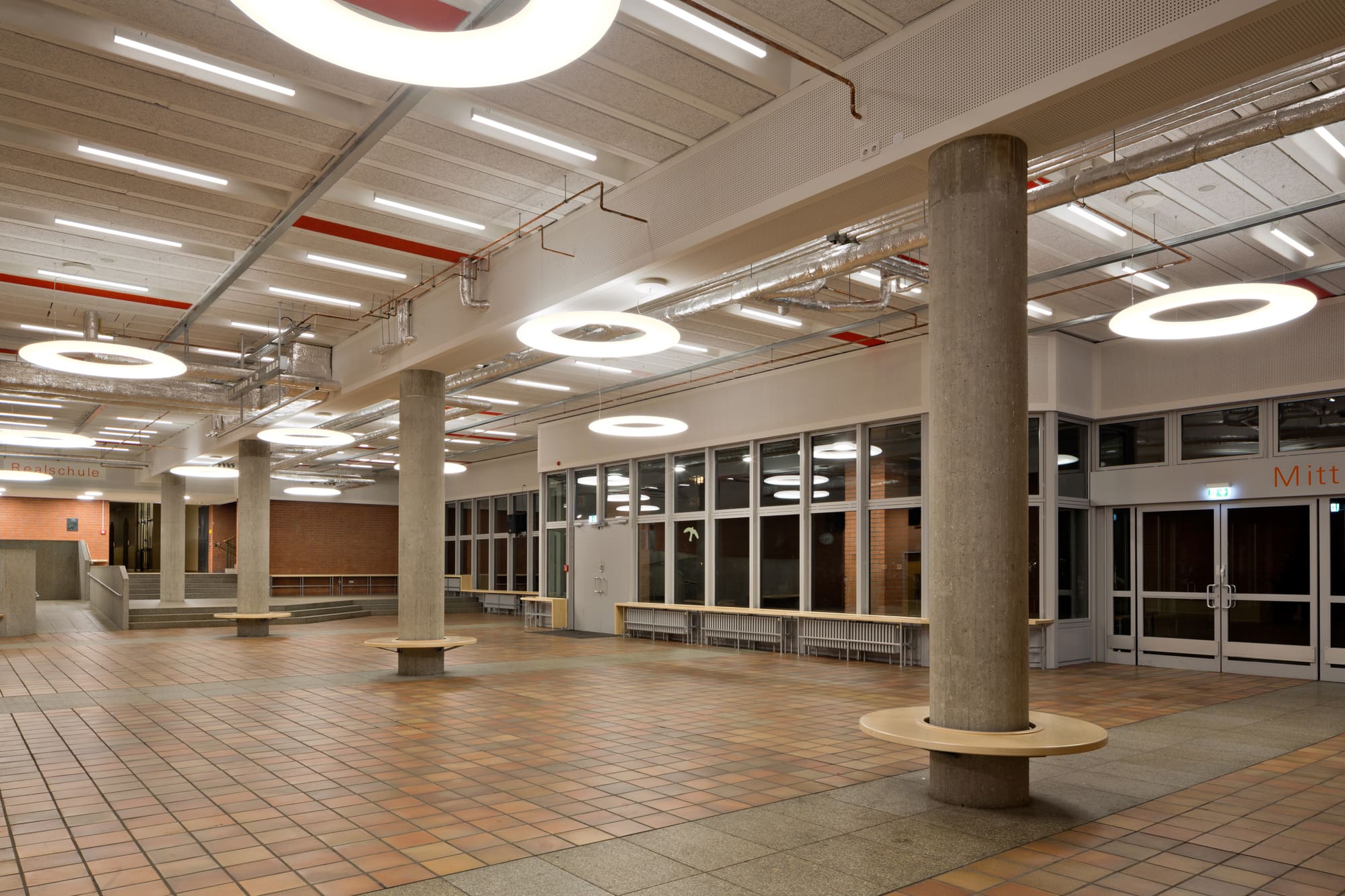 Pausenhalle mit freigelegter Rippendecke und runden Leuchten – Akustische Sanierung der Pausenhalle der Carl-von-Linde-Realschule