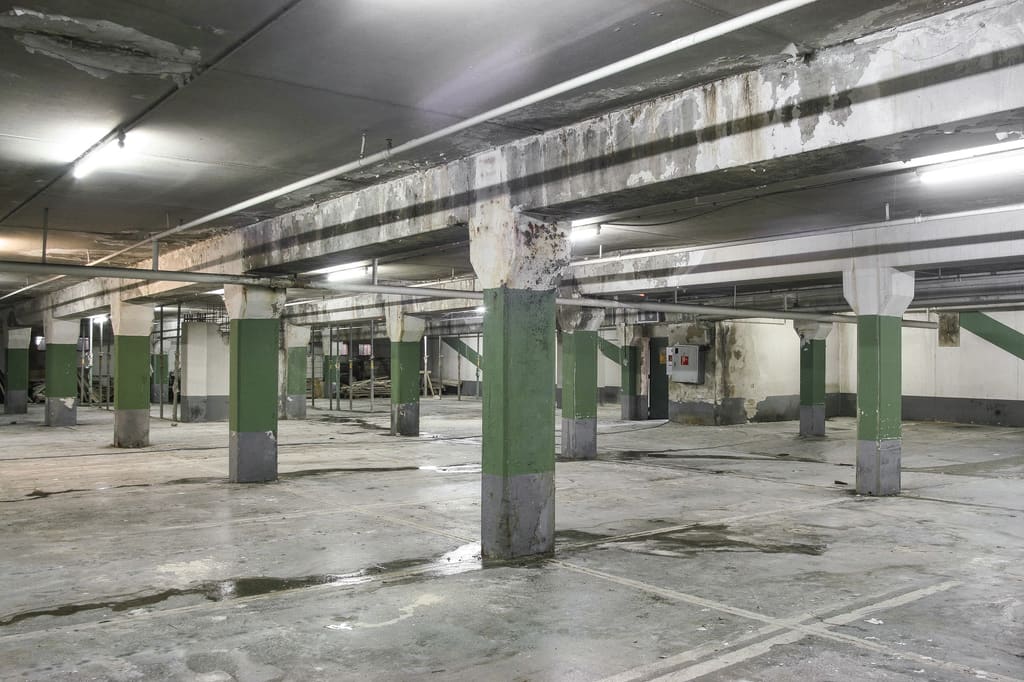 Tiefgarage vor der Instandsetzung mit geschädigten Oberflächen – Betoninstandsetzung der V-Markt-Tiefgarage bei laufendem Betrieb